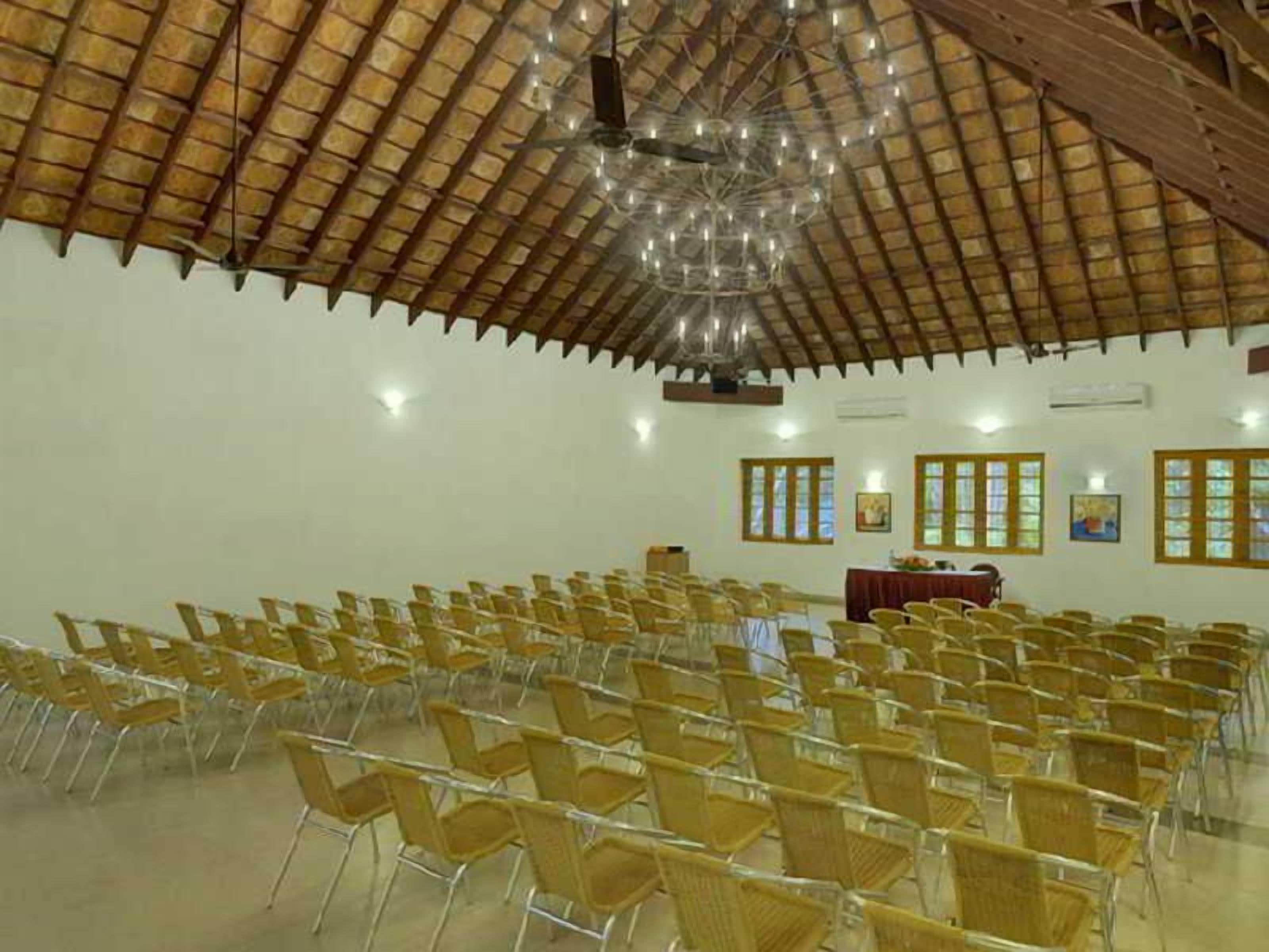 A large hall with rows of chairs, a wooden ceiling, and a chandelier.