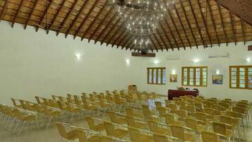 A large hall with rows of chairs, a wooden ceiling, and a chandelier.