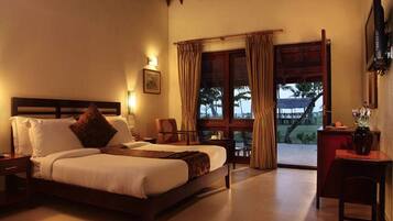 A bedroom with a bed, a desk, a chair, and a balcony with curtains.