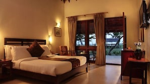 A bedroom with a bed, a desk, a chair, and a balcony with curtains. - Abad Turtle Beach (Ambalapuzha)