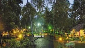 A pathway leading through a forested area with trees and a small building on the right. - Abad Turtle Beach (Ambalapuzha)