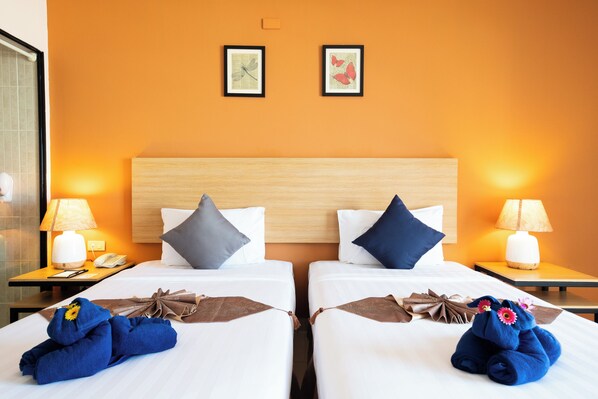 A hotel room with two beds, each with a pillow, a bedside table with a lamp, and a framed picture on the wall. - The Vogue Hotel, Pattaya (Pattaya)
