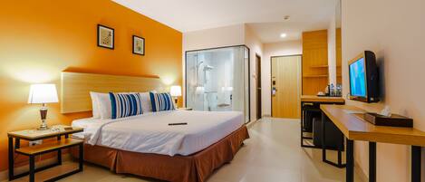 A hotel room with a bed, bedside tables, a desk, a TV, and a shower area.
