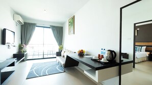 A modern hotel room with a kitchen area, a dining table, and a large window with curtains. - The Vogue Hotel, Pattaya (Pattaya)