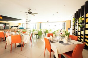 A spacious dining area with multiple tables and chairs, a ceiling fan, and large windows allowing natural light. - The Vogue Hotel, Pattaya (Pattaya)