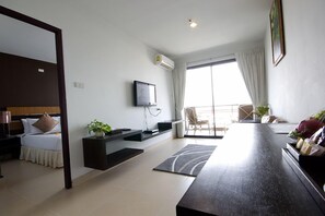 Una habitación de hotel moderna con una cama, un televisor montado en la pared, un balcón con una silla y un escritorio con una planta.
