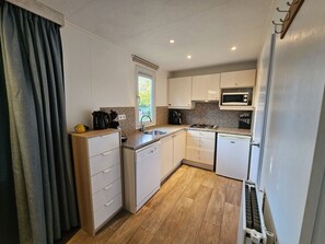 A compact kitchen with white cabinets, a microwave, a sink, and a dishwasher. - RBR 2464 - Beach Resort Kamperland by Interhome (Kamperland)