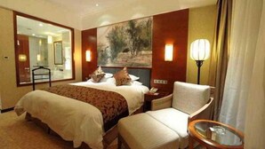 A hotel room with a large bed, a chair, a small table, a painting on the wall, and a lamp. - Hengshan Park (Beijing)