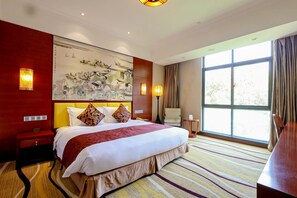 A hotel room with a large bed, a painting on the wall, a desk, and a window with curtains. - Hengshan Park (Beijing)