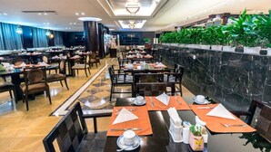 A spacious dining area with multiple tables and chairs, a marble wall with greenery, and a modern ceiling design. - Hengshan Park (Beijing)
