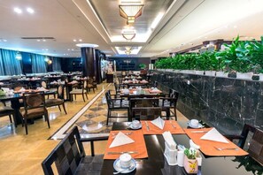 A spacious dining area with multiple tables and chairs, a marble wall with greenery, and a modern ceiling design. - Hengshan Park (Beijing)
