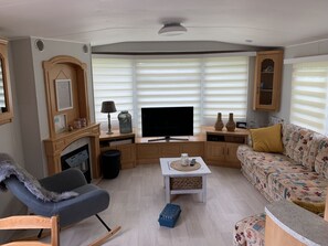 A living room with a fireplace, television, sofa, and a small table with a tray. - RBR 1023 - Beach Resort Kamperland by Interhome (Kamperland)
