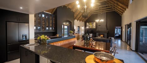 A modern kitchen with dark cabinetry, a central island, and a wooden ceiling.