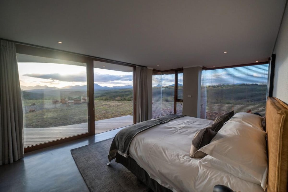 Un dormitorio con una cama grande, vistas al exterior y una puerta corrediza de cristal.