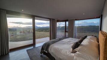 Une chambre avec un grand lit, une vue sur l’extérieur et une porte-fenêtre coulissante.