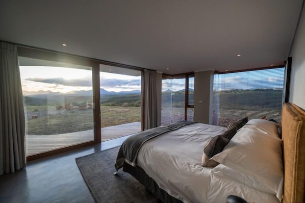 Un dormitorio con una cama grande, vistas al exterior y una puerta corrediza de cristal.