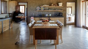 Una cocina moderna con armarios de madera, una mesa de comedor con sillas y una estación para café.