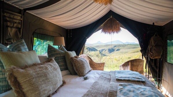 A tent with a bed, pillows, a hanging lamp, and a view of the landscape. - Gondwana Game Reserve (Mossel Bay)