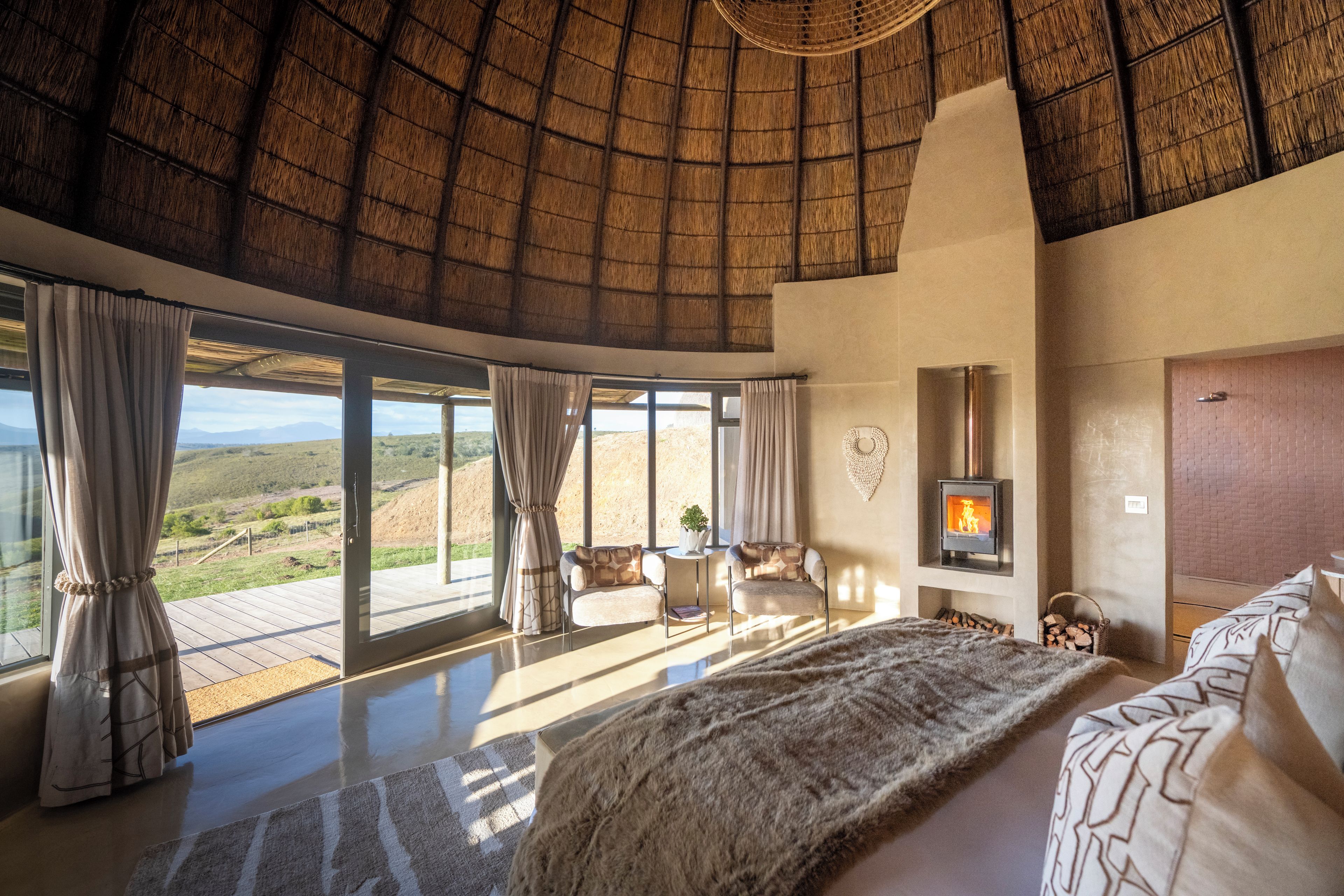 A spacious bedroom with a large bed, a fireplace, and a view of the countryside.