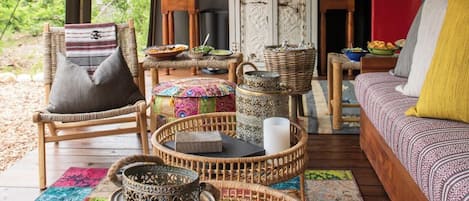 A cozy interior with a wicker sofa, a wooden chair, and a dining area with a table set for two.