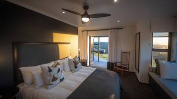 A hotel room with a large bed, a ceiling fan, a view of the outdoors, and a seating area by the window.