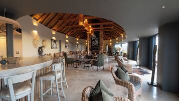A spacious lounge area with a curved ceiling, wicker furniture, and a bar counter.