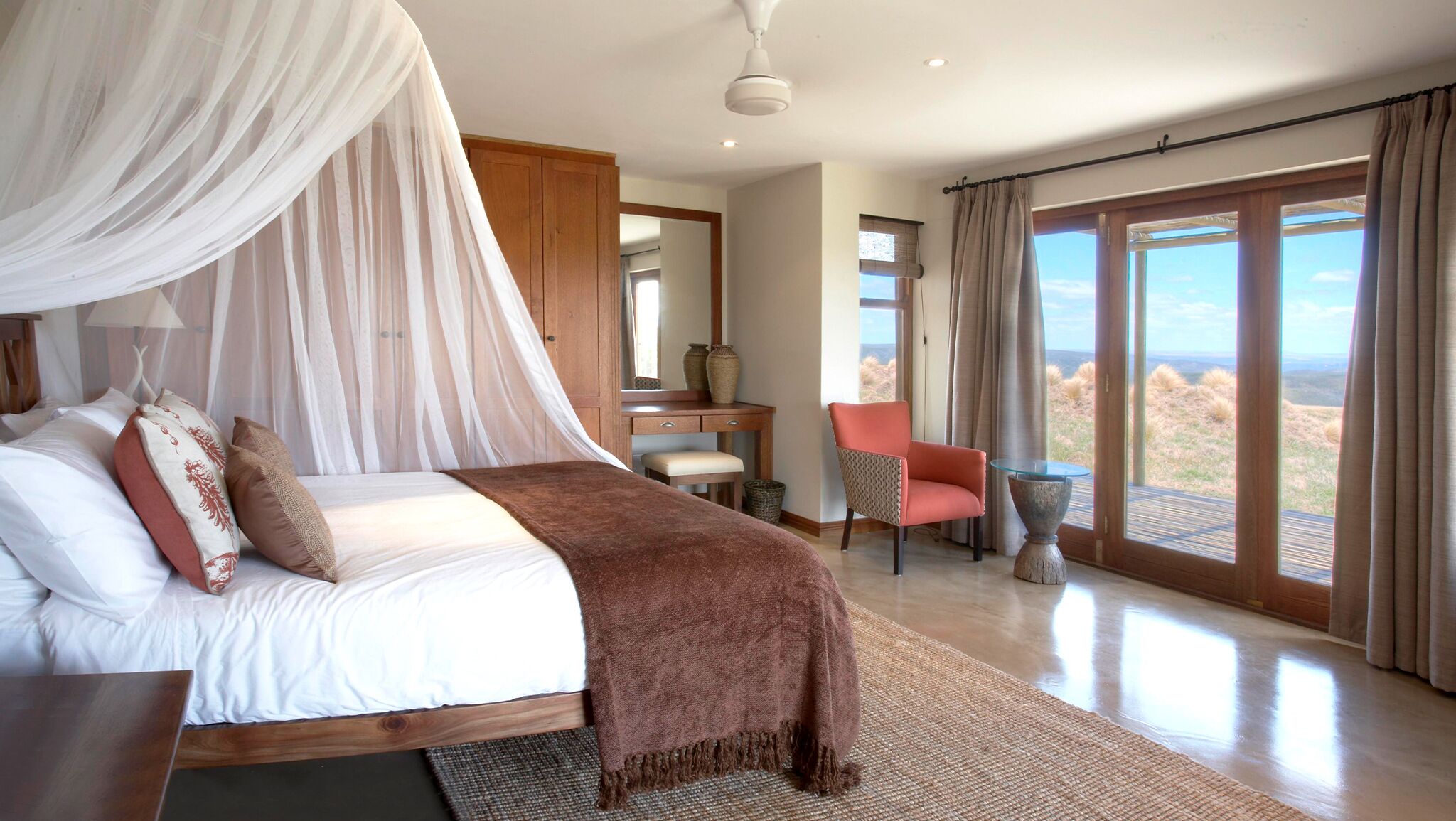 Un dormitorio con cama, escritorio, silla y vistas al exterior.