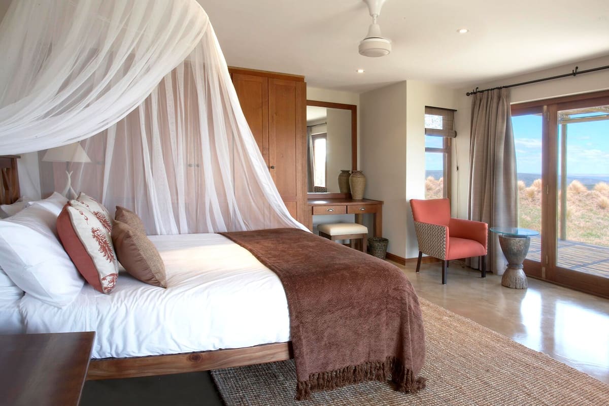 Un dormitorio con cama, escritorio, silla y vistas al exterior.