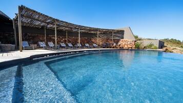 Une piscine aux eaux cristallines, dotée de chaises longues et d’une pergola.