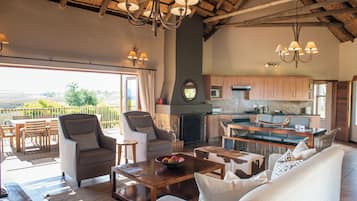 A spacious living area with a large window, a fireplace, and a kitchen with wooden cabinets.