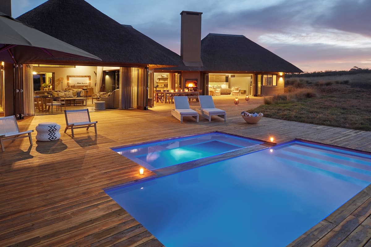 Una casa moderna con una amplia terraza, dos piscinas y una chimenea.