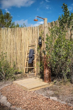 A wooden deck leading to a wooden door, a towel hanging on a wooden ladder, and a lantern post. - Gondwana Game Reserve (Mossel Bay)