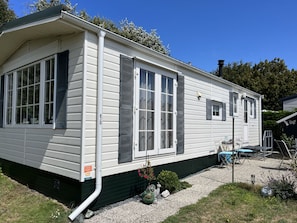 Ein Bungalow mit Veranda, großen Fenstern und einem kleinen Garten.