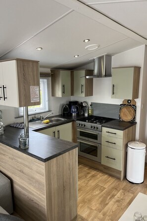 A compact kitchen with a central island, built-in oven, and a stove. - CS 53 - Vakantiepark Callassande by Interhome (Callantsoog)