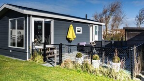 A single-story house with a covered patio, a fenced yard, and a number '34' sign. - CS 34 - Vakantiepark Callassande by Interhome (Callantsoog)