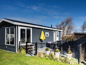 Een gelijkvloers huis met een overdekt terras, een omheinde tuin en een huisnummer '34'.