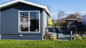 A modern house with a large window, a yellow umbrella, and a fenced yard. - CS 34 - Vakantiepark Callassande by Interhome (Callantsoog)