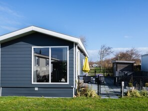 Een modern huis met een groot raam, een gele paraplu en een omheinde tuin.
