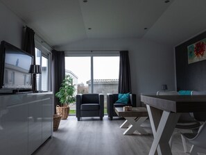 Un salon moderne avec un téléviseur, un coin salon et une table à manger.
