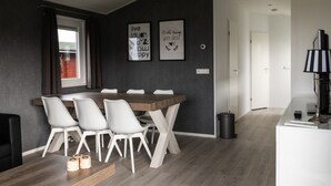A modern dining area with a wooden table and white chairs, a grey accent wall with motivational posters, and a view of a brick building outside. - CS 34 - Vakantiepark Callassande by Interhome (Callantsoog)
