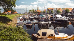 A marina with boats docked, a wooden dock, and a town with buildings in the background. - RBR 6062 - Beach Resort Kamperland by Interhome (Kamperland)