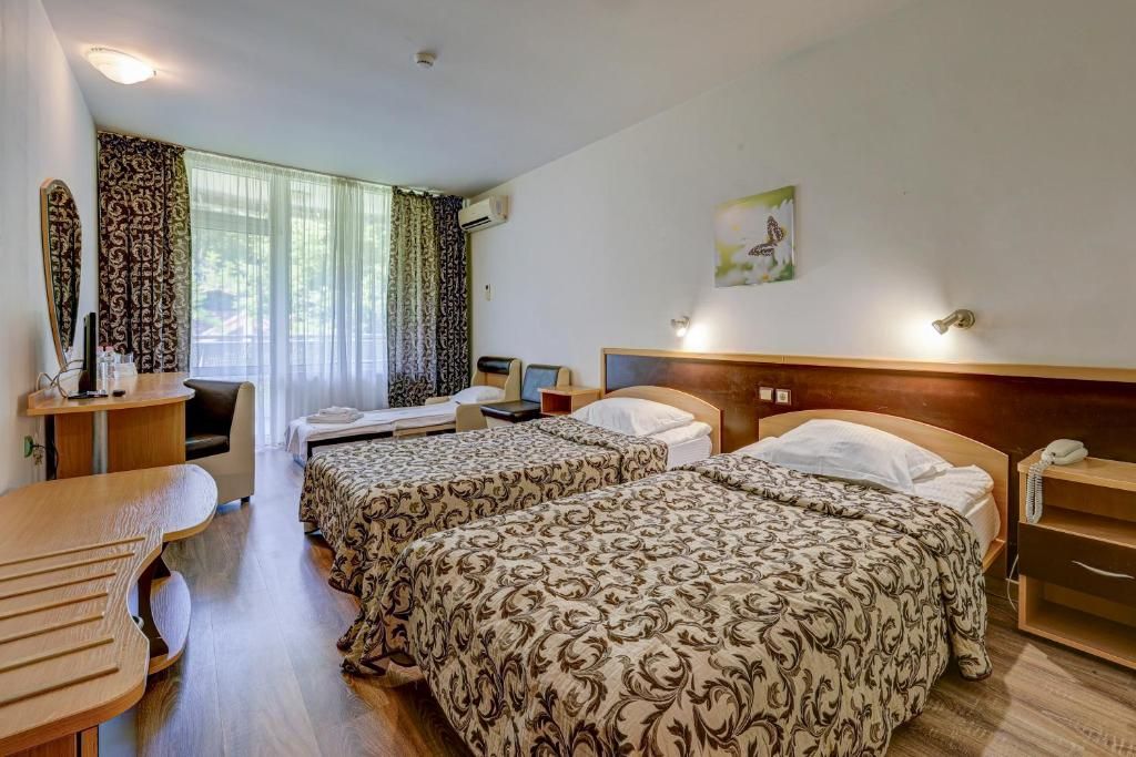 A hotel room with two beds, a desk, a chair, a telephone, and a painting on the wall.