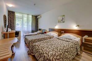 Ett hotellrum med två sängar, ett skrivbord, en stol, en telefon och en tavla på väggen.