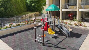 A playground with a slide, climbing structure, and a green-roofed shelter.