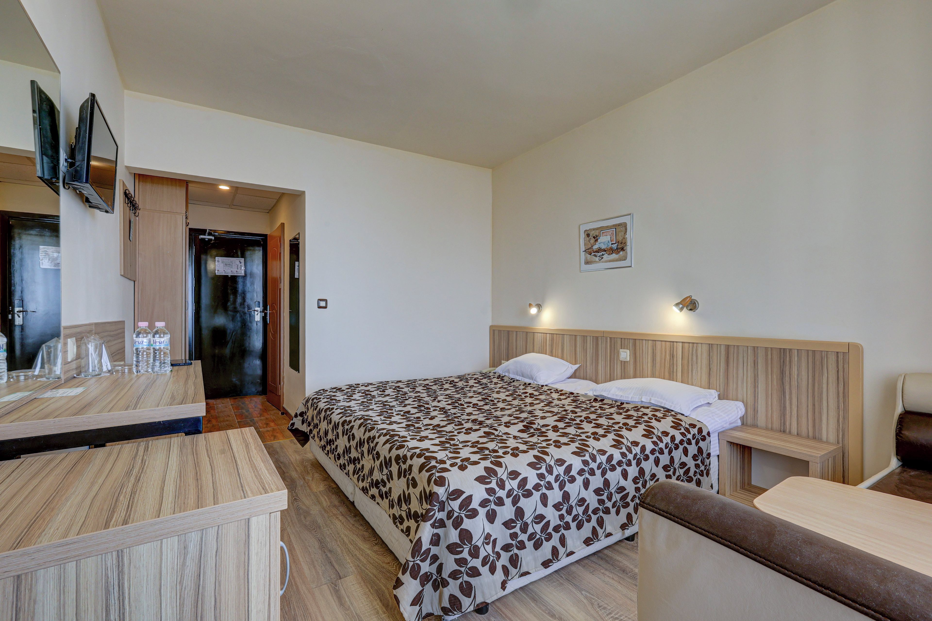 Un dormitorio con cama, mesitas de noche, un escritorio y un espejo.