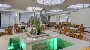 Un comedor amplio con mesas y sillas, un centro de mesa decorativo y una araña.