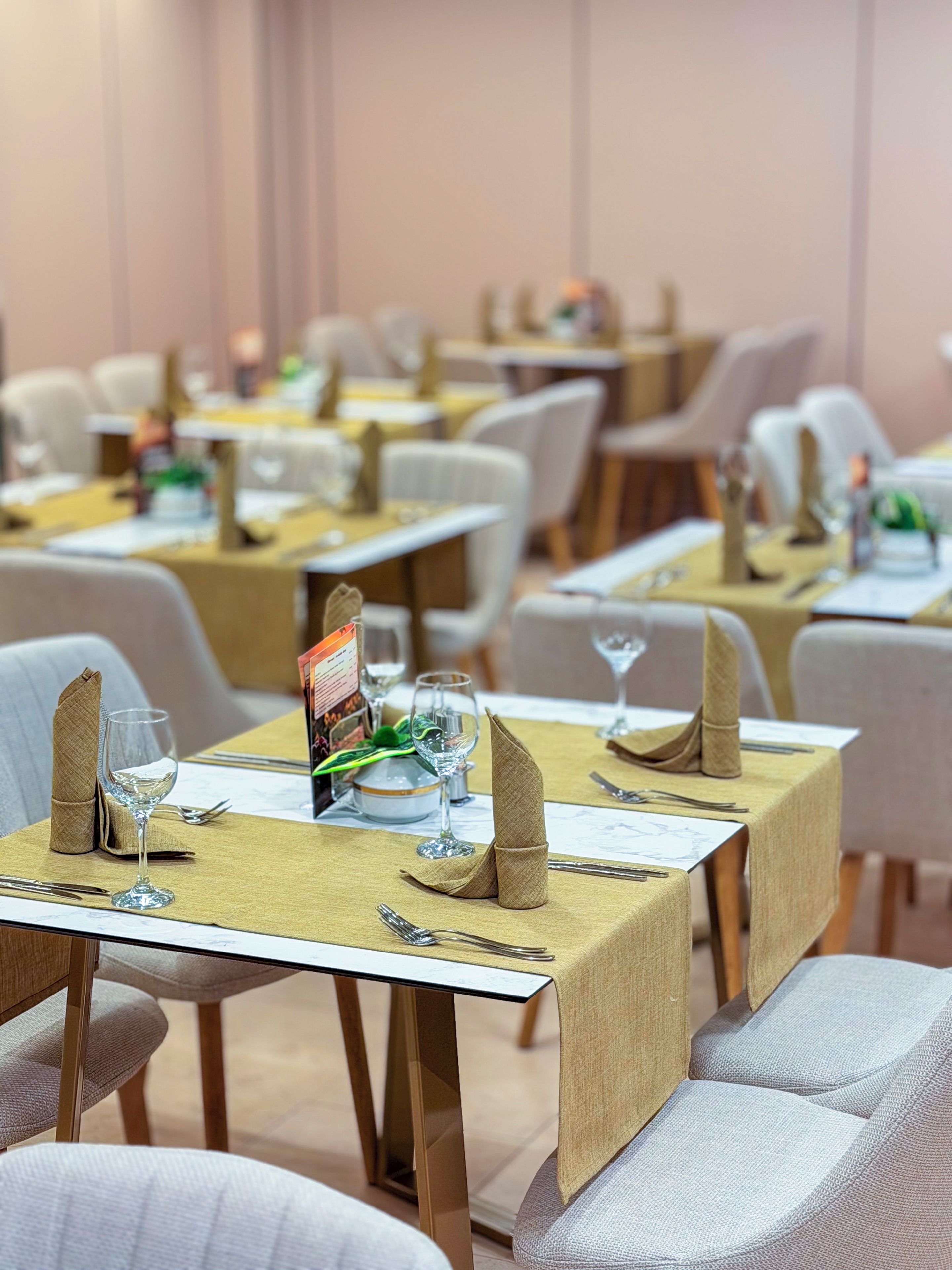 Un espace repas avec des tables dressées, chacune agrémentée d’un présentoir à menus, de verres et de serviettes pliées.
