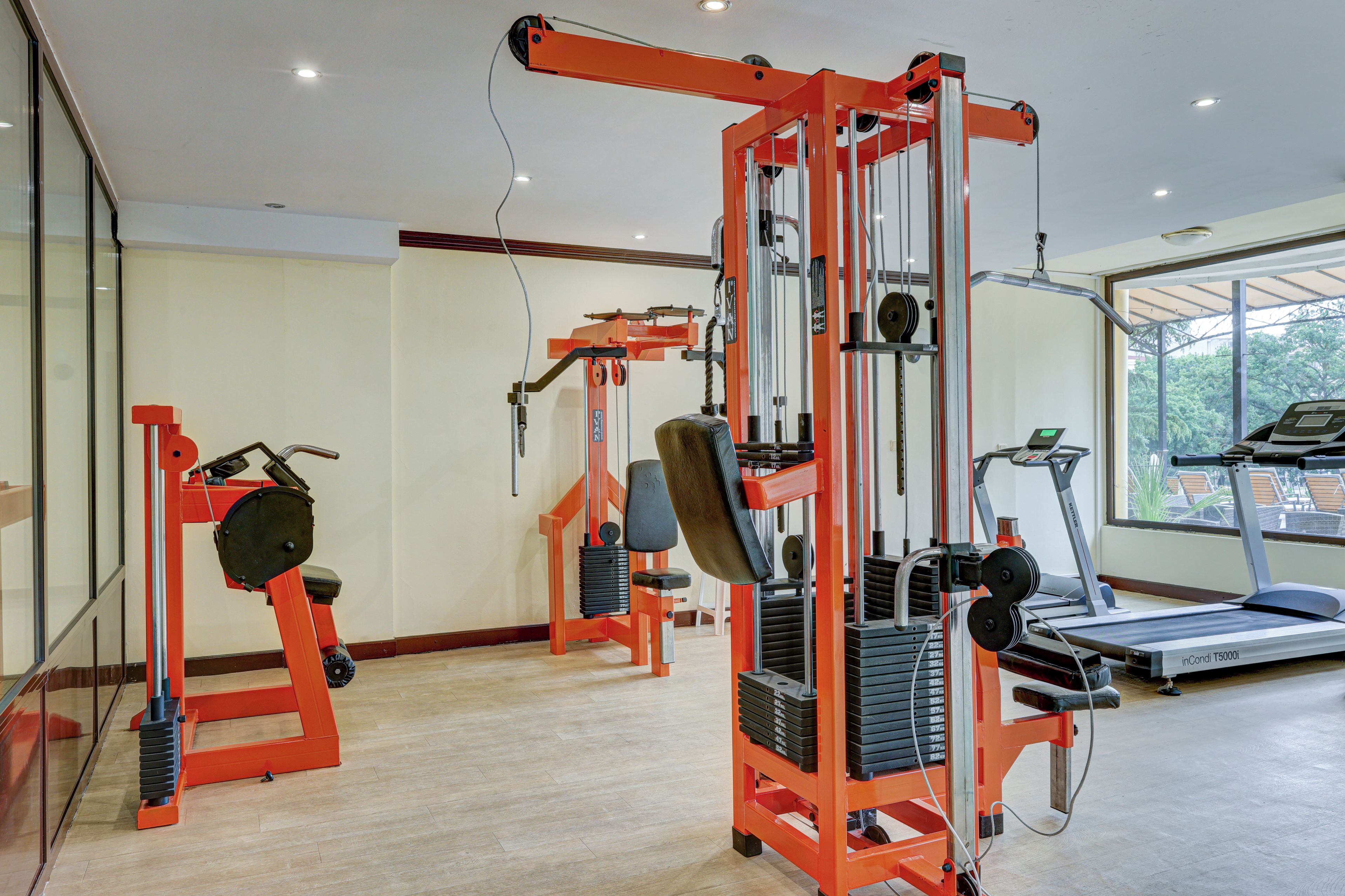 A gym with weight machines, a treadmill, and a large window.