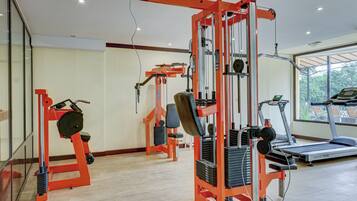A gym with weight machines, a treadmill, and a large window.