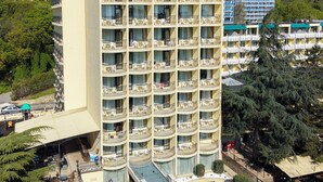 Un hotel de varios pisos con balcones, una piscina y un cartel que dice 'Shipka Hotel'.